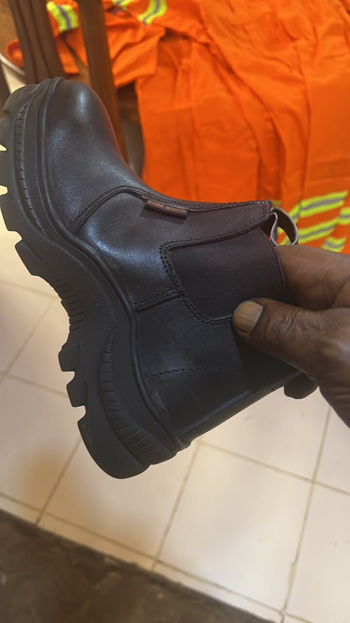 Black lace-up boot held over orange workwear